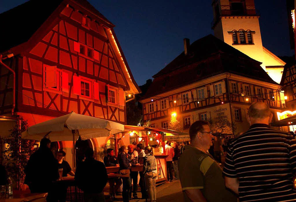 Beleuchtete Fachwerkhäuser am Abend mit Besuchern eines Festes