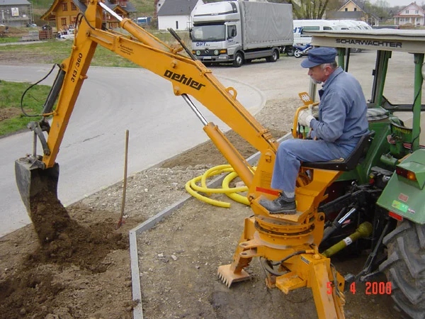 Mann bedient einen Bagger-Anbau an einem Traktor