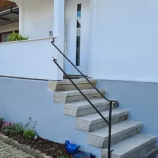Eingangstreppe mit Geländer an einem hellen Haus