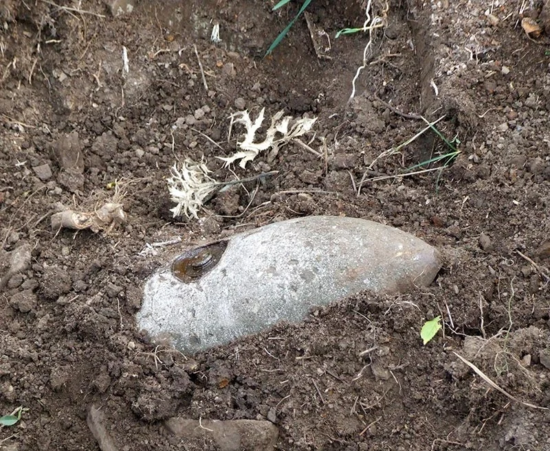 Im aufgewühlten Erdboden liegender Bombenkörper