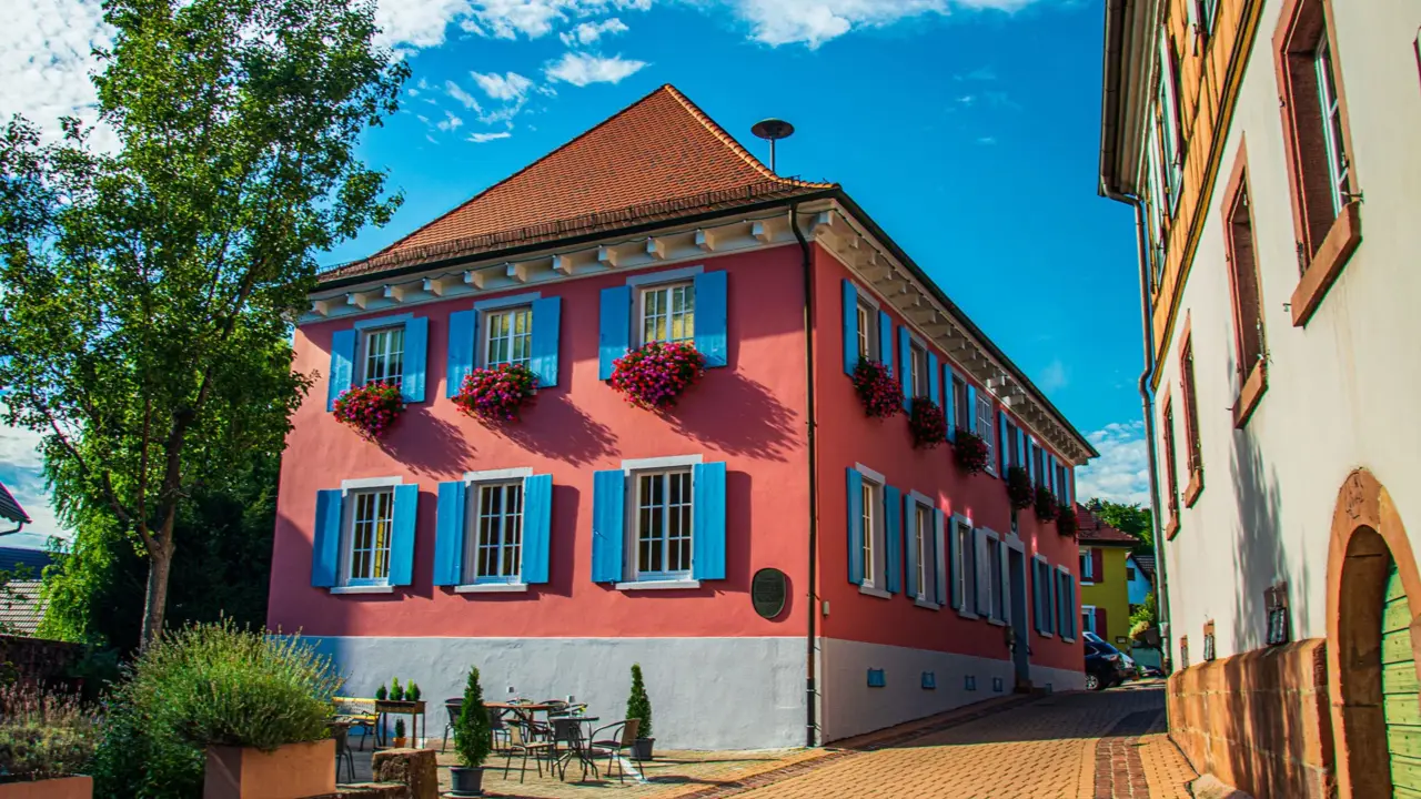 Rathaus Münchweier: rotes Gebäude mit blauen Fensterläden und Blumenschmuck