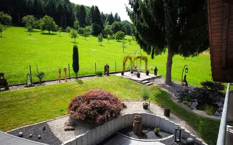 Gepflegter Garten mit Rasen und Blick auf Wiesen und Wald