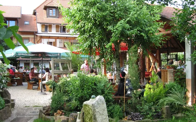 Gartenwirtschaft unter Bäumen vor dem Gebäude des Weinguts Isele