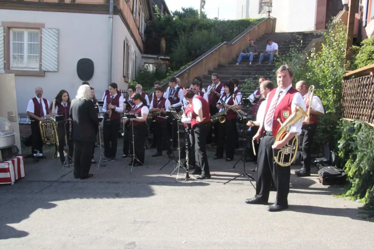 Musikverein spielt im Freien vor einer Treppe, im Vordergrund ein Mann mit Tuba