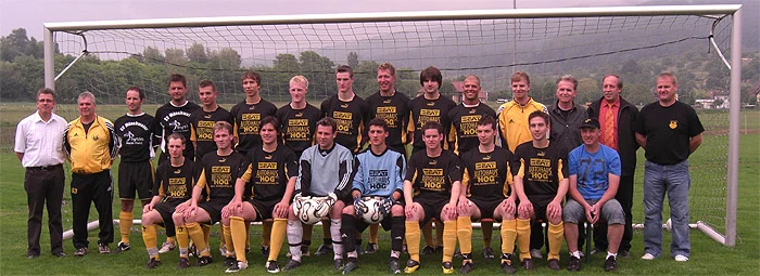Mannschaftsfoto einer Fußballmannschaft in schwarzen Trikots vor dem Tor