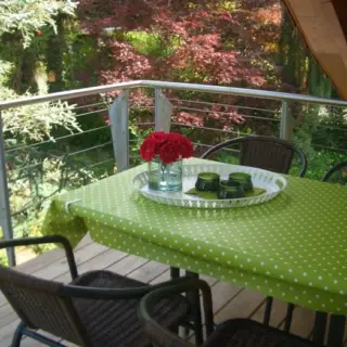 Terrasse mit Tisch, grüner Tischdecke und Blumenstrauß