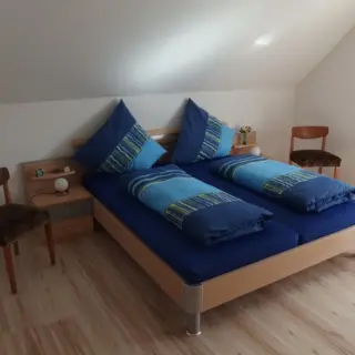 Schlafzimmer unter der Dachschräge mit blauem Doppelbett
