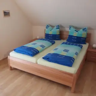 Schlafzimmer unter der Dachschräge mit Holzbett und blauer Bettwäsche
