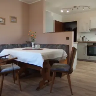 Essbereich mit gedecktem Tisch und Eckbank, im Hintergrund die Küche