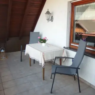 Balkon mit Tisch, Blumen und Stuhl