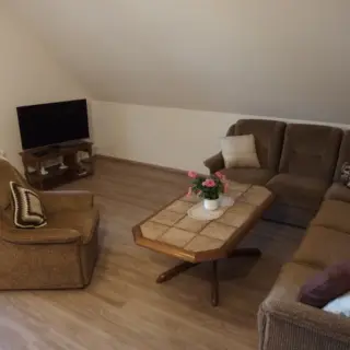 Wohnzimmer mit Sofa, Sessel, Couchtisch und Fernseher
