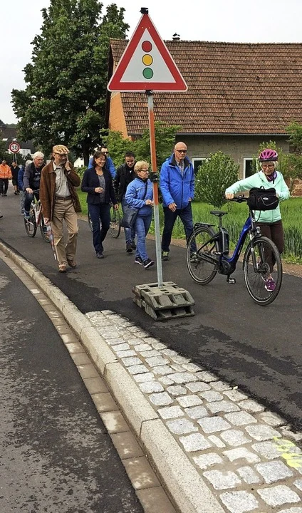 Fußgänger und eine Radfahrerin auf einem Weg am Ortsrand