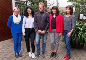 Fünf Personen stehen in einem Hof