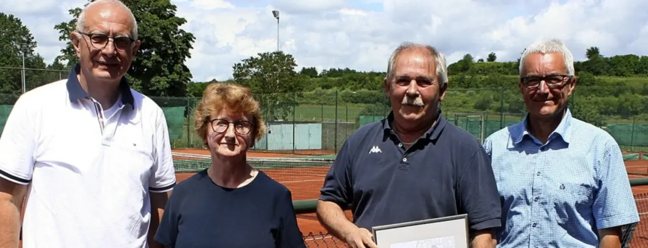 Frau und Mann vor einem Tennisplatz, er hält eine Urkunde
