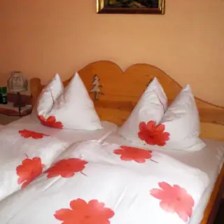 Doppelbett mit weißer Bettwäsche und roten Kleeblattmotiven